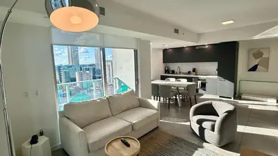 a living room with a couch and a chair and a kitchen at Rare Corner Unit Private Terrace & Sunset Views in Miami
