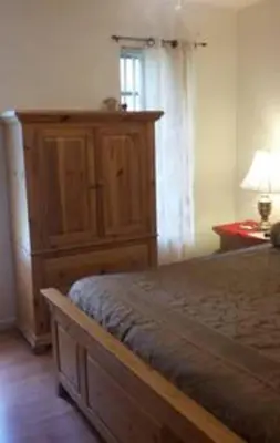 a bedroom with a bed and a wooden cabinet at Flats Hospitality in Plantation