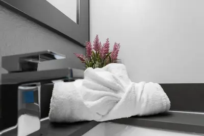 a towel sitting on a bathroom sink with a flower at Sunny 1BR Unit With Free Parking Prime Location in Miami