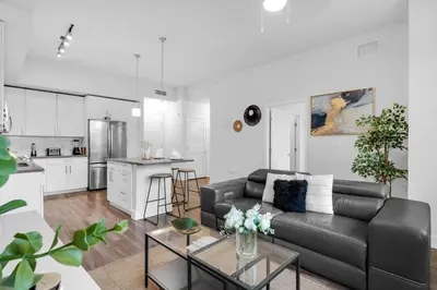 a living room with a black couch and a kitchen at Sunny 1BR Unit With Free Parking Prime Location in Miami