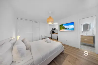 a white bedroom with a bed and a bathroom at Chic Miami Studio - Gym, BBQ, Free Parking in Miami