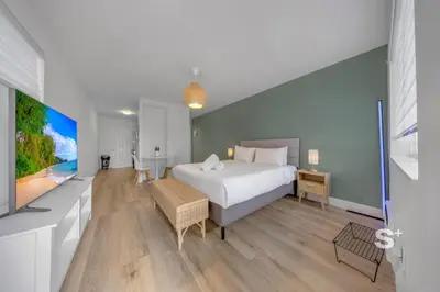 a bedroom with a large white bed and a tv at Stylish Studio - Parking & Gym Near Aventura in Miami