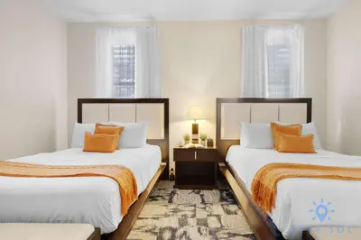 two beds in a room with white walls and orange pillows at Stylish Apartment 1BR - 2BTH in Miami