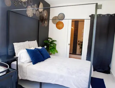 a bedroom with a bed with blue pillows and a mirror at Boho Oasis 2 in Homestead