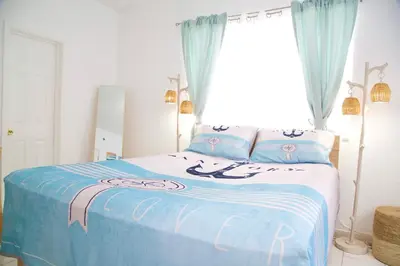 a bedroom with a bed with blue sheets and a window at Miami2 Beach Stay 3 min to Ocean in Miami Beach