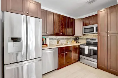 a kitchen with wooden cabinets and a stainless steel refrigerator at Orange Dream on the Water in Fort Lauderdale
