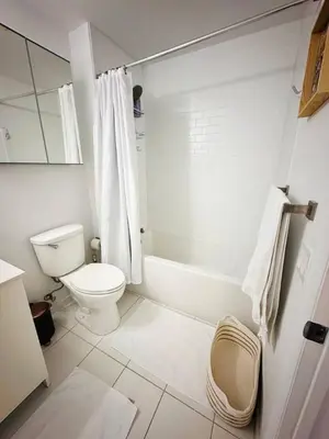 a white bathroom with a toilet and a bath tub at Art-filled Loft 180 Views, Rooftop Pool, Parking in Miami