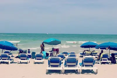 a group of lawn chairs and umbrellas on a beach at Departamento sobre la Playa con vista a la Collins Ave in Sunny Isles Beach