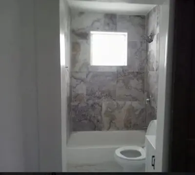 a bathroom with a toilet and a tub and a window at Apartamento a 5 minutos de Brickel no amubleado para estancias largas in Miami