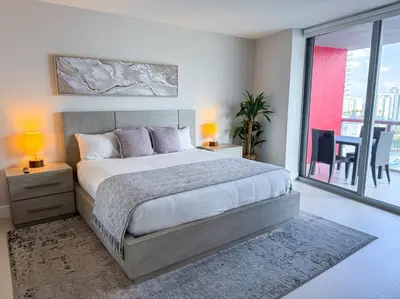 a bedroom with a large bed and a balcony at Luxury 3 bedroom condo with pool in Hallandale Beach