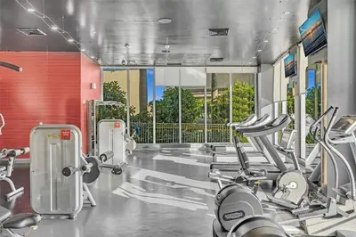 a gym with a row of treadmills and cardio machines at Luxury 3 bedroom condo with pool in Hallandale Beach
