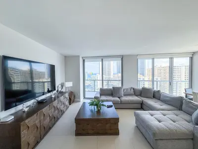 a living room with a couch and a large tv at Luxury 3 bedroom condo with pool in Hallandale Beach