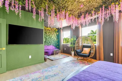 a bedroom with a bed and a flat screen tv at Luxury Glow Villa Miami - 4K Private Cinema, Heated Pool & Spa, Game Room - 5BR Lakefront Estate for 12 Guests in Hammocks