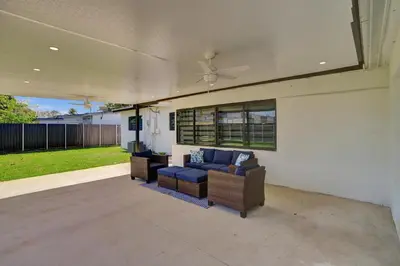 a patio with a blue couch and wicker chairs at Luxe Haven Near Aventura in Ives Estates