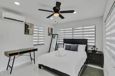 a bedroom with a bed and a desk and a ceiling fan at Serene Suite Near Aventura in Ives Estates