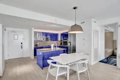 a kitchen with blue cabinets and a white table and chairs at Luxury Beachfront Two Bedroom Condo - W Residences in Fort Lauderdale