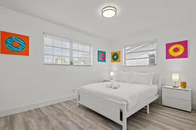 a white bedroom with a bed and paintings on the wall at Pool, golf & 4 mi. from the beach & The Hard Rock in Hollywood