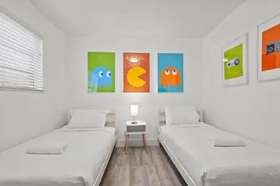 two beds in a white room with paintings on the wall at Pool, golf & 4 mi. from the beach & The Hard Rock in Hollywood