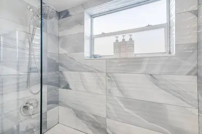 a bathroom with a glass shower with a window at Beach, Pool & Las Olas Getaway in Fort Lauderdale