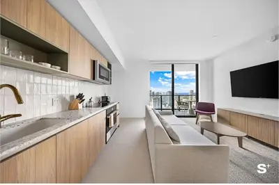 a kitchen with a couch and a sink and a tv at City Luxe Retreat Modern 2-BD with Water Views in Miami