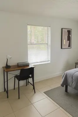 a bedroom with a desk and a bed and a window at Pacifica Fort Lauderdale Airport in Dania Beach
