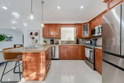 a kitchen with wooden cabinets and a stainless steel refrigerator at Casa Brisa - Stylish BBQ Near heart of Kendall in Miami