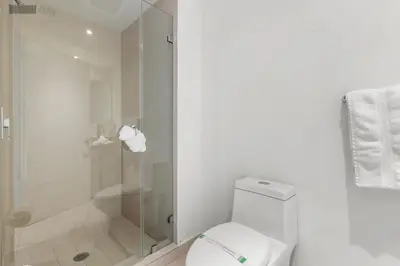 a white bathroom with a shower and a toilet at City Lights and Skyline Nights - High-Floor Stay in our Luxury Apartment in Hollywood
