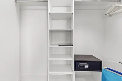 a closet with white shelves and a refrigerator at City Lights and Skyline Nights - High-Floor Stay in our Luxury Apartment in Hollywood
