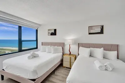 two beds in a bedroom with a large window at Classic Resort Amenities Condo Steps from the Beach with Gym and Pool 1208 in Miami Beach