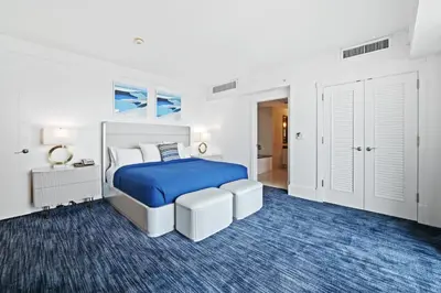 a white bedroom with a bed and a blue rug at Ritz-Carlton Luxury Oceanfront 2BR on 16th Floor in Fort Lauderdale