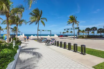 a sidewalk next to a beach with palm trees at 16th Floor Luxury 2 Bedroom - Ocean Views & Luxury in Fort Lauderdale
