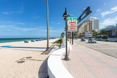 a street sign on a sidewalk next to the beach at W Residences 2 Bed Unit - Beachfront and Luxe Stay in Fort Lauderdale