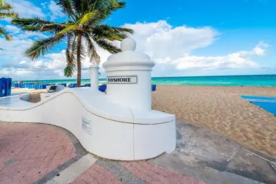 a white building on the beach with a palm tree at W Residences 2 Bed Unit - Beachfront and Luxe Stay in Fort Lauderdale