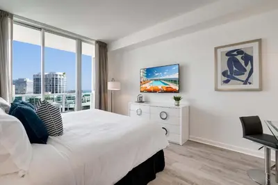 a white bedroom with a large bed and a window at Cocktails & Coffee with bay & city view balconies in Miami
