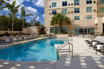a pool at a hotel with lounge chairs and a building at Hyatt Place Miami Airport East in Miami