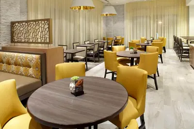 a dining room with tables and yellow chairs at Hyatt Place Miami Airport East in Miami