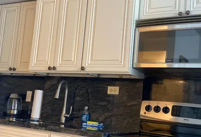 a kitchen with white cabinets and a sink and a microwave at All you need around you in Sunny Isles Beach