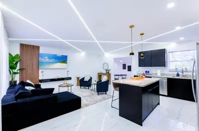 a kitchen and living room with a couch and a table at The Glow House w Cinema, Disco, Pool, BBQ, 9 beds in Ives Estates