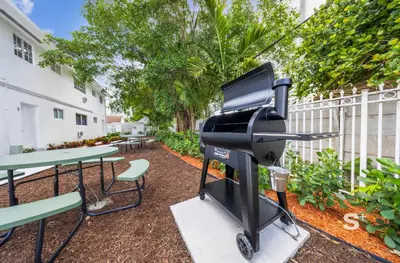 a bbq grill and picnic tables in a courtyard at Stylish 1-BD Apt in Miami Gym, BBQ, Free Parking in Miami
