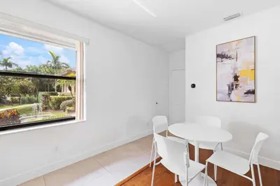 a white dining room with a white table and chairs and a window at Spacious home wpool tennis court in Sunrise