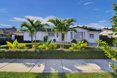 a white house with palm trees and a sidewalk at Villa Miami Oasis and Heated Pool in University Park