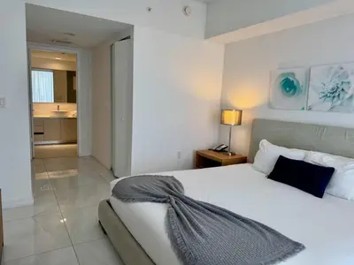 a bedroom with a white bed and a bathroom at 1BR on Miami Beach with Beach Service & Near Mall in Hallandale Beach