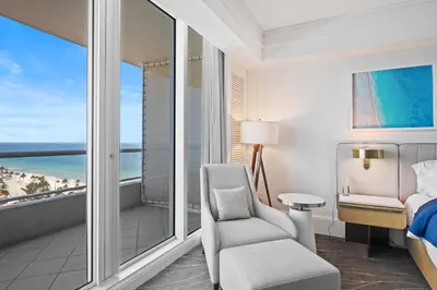 a bedroom with a bed and a chair and a balcony at Ritz-Carlton Luxury Oceanview 3-Bedroom Residence in Fort Lauderdale