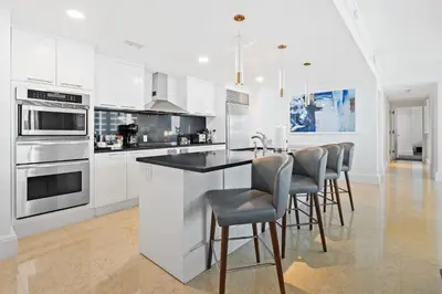 a kitchen with white cabinets and a bar with stools at Ritz-Carlton Luxury Oceanview 3-Bedroom Residence in Fort Lauderdale