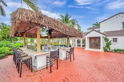 an outdoor bar with chairs and a thatched roof at Grand historic Residence Walk to beach Heated Pool Outdoor kitchen Hibiscus Key Residences in Fort Lauderdale