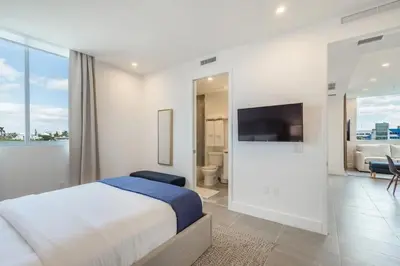 a white bedroom with a bed and a tv on a wall at Apto Moderno a 5min da Praia em South Beach in Miami Beach