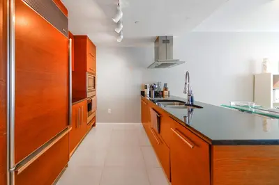 a kitchen with wooden cabinets and a black counter top at Panoramic City Views From 45th Floor Brickell Condo in Miami