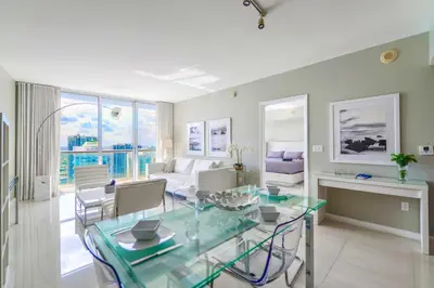 a dining room and living room with a glass table at Panoramic City Views From 45th Floor Brickell Condo in Miami