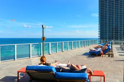 a group of people laying on lounge chairs on the beach at Live The Perfect Vacations in a Condo From The High in Hollywood