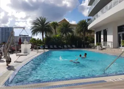 two people swimming in a large swimming pool at Studio Beach Apmt 2 Full Q Beds, Amazing View in Hallandale Beach